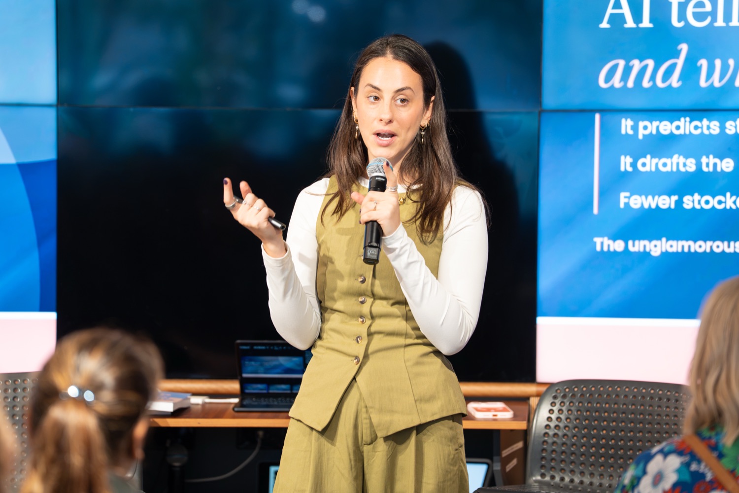Gabi Saper speaking with a microphone at the SHE-com Roadshow